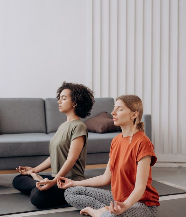 Woman in a peaceful yoga pose in a brightly lit room.